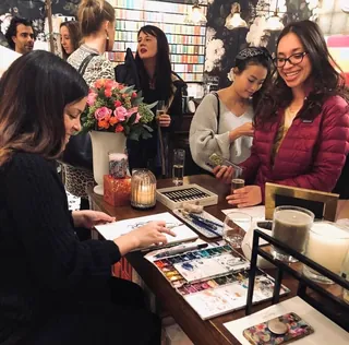 Woman painting at craft fair with shoppers looking at art
