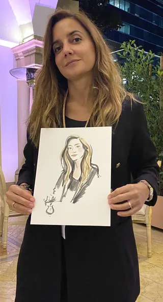 Woman holding a portrait sketch of herself outdoors at night