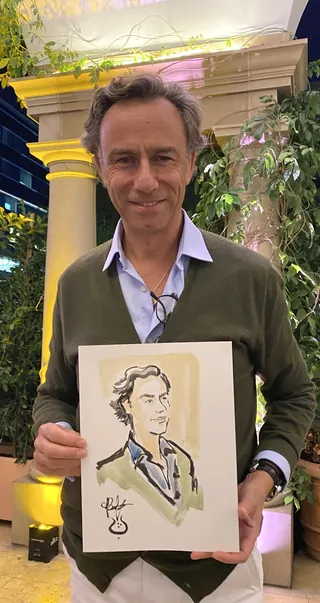 Man holding caricature portrait of himself outdoors at night