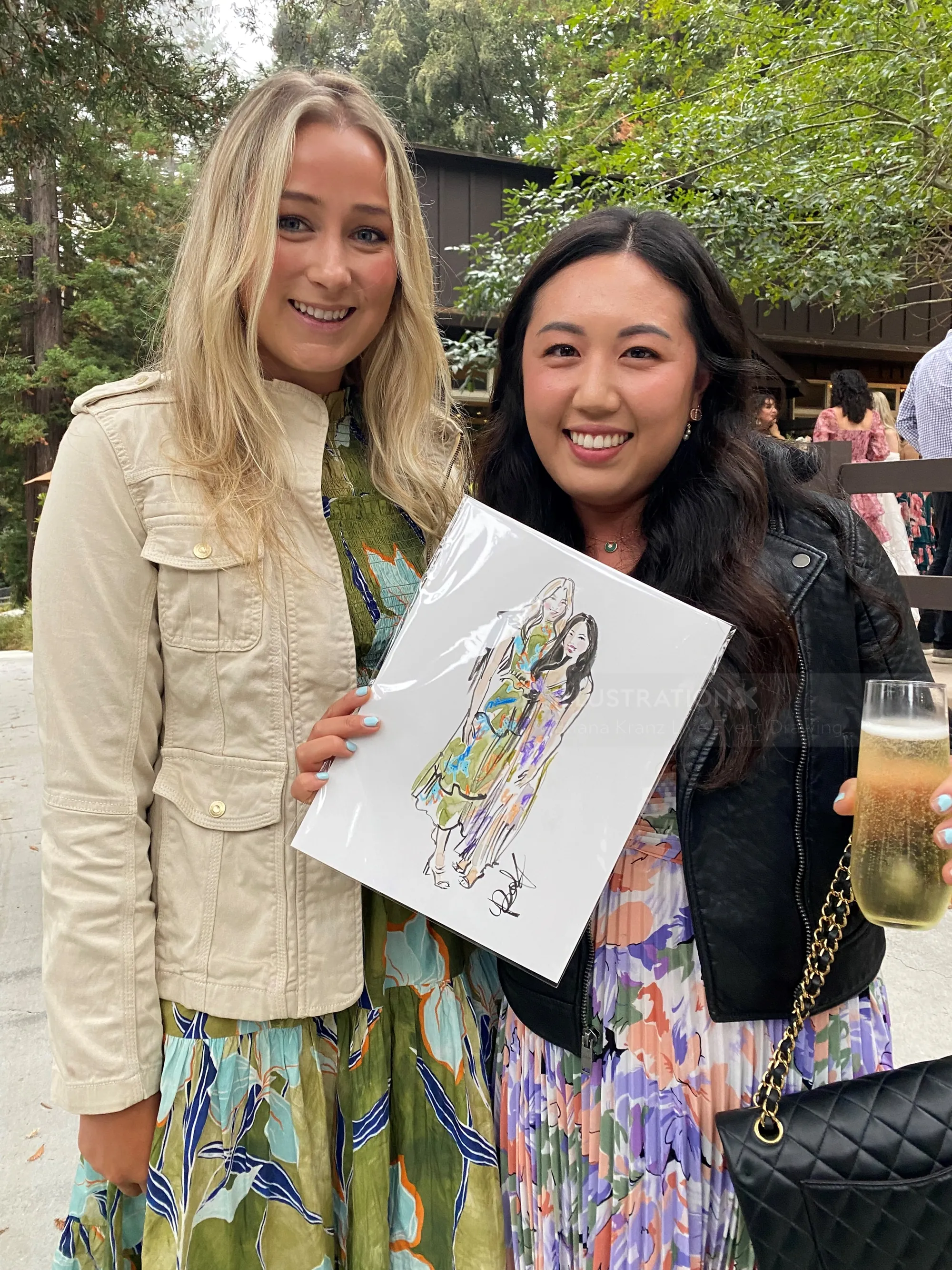 Two women outdoors, one holding an art print, both smiling.