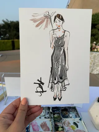 Hand holding a quick ink and watercolor portrait of a woman in a dress