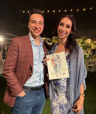 Smiling couple holding caricature portrait at nighttime event