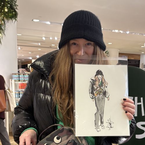 Person wearing black hat and jacket holding fashion sketch by Briana Kranz
