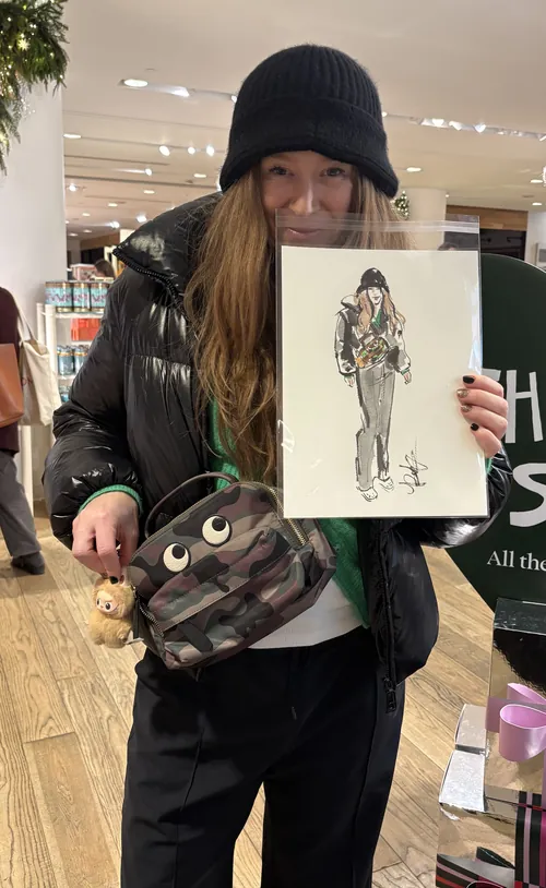 Person wearing black hat and jacket holding fashion sketch by Briana Kranz