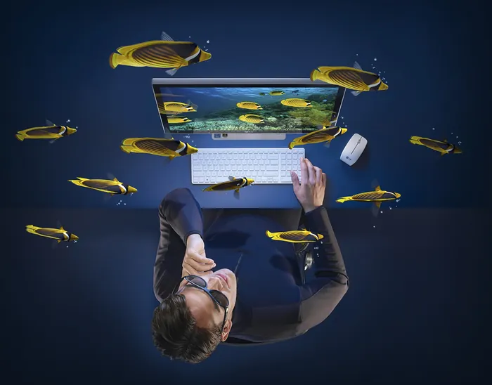 Man working on laptop surrounded by floating fish, artwork by CUBE