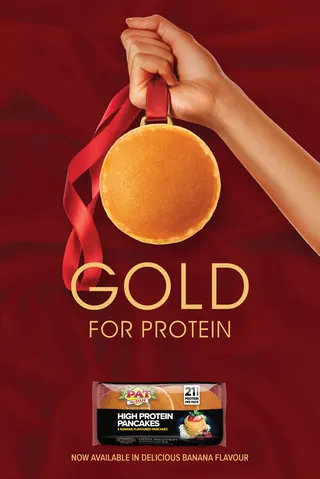 Hand holding a pancake medal with a red ribbon against red background