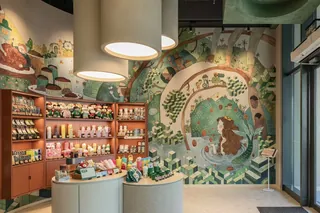 Store interior with shelves of products and a large bear mural on wall