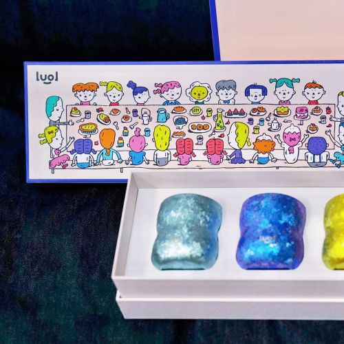 Four gummy bear-shaped candles in different colors in a white gift box