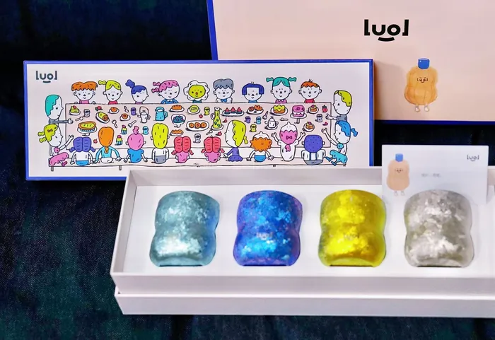 Four gummy bear-shaped candles in different colors in a white gift box
