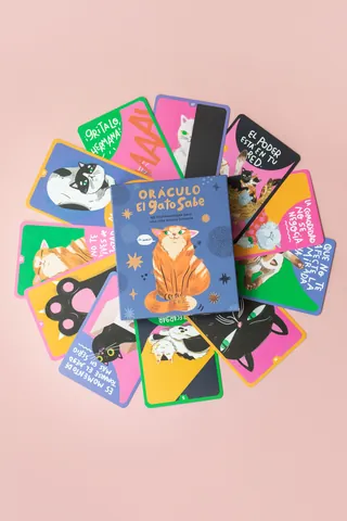 Cat-themed oracle cards fanned out in a circle on a pink surface