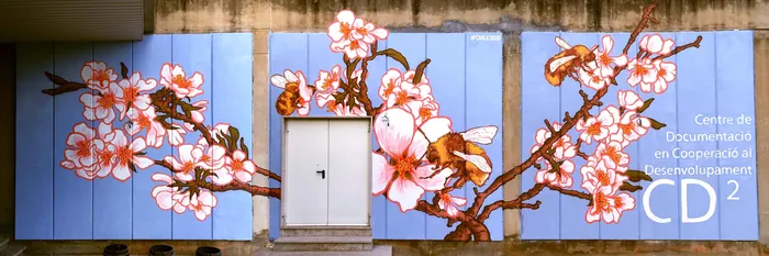 Mural of blooming cherry blossom branches on blue wall by Carles Garcia O'Dowd
