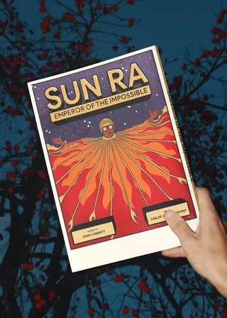 Hand holds Sun Ra Emperor of the Impossible poster with fiery design