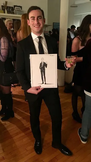 Man in suit holding portrait sketch at event by Caroline So