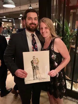 Man and woman in formal attire holding caricature portrait by Caroline So Live Event Drawing