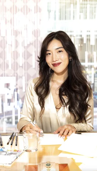 Smiling woman writing at desk with papers and pens