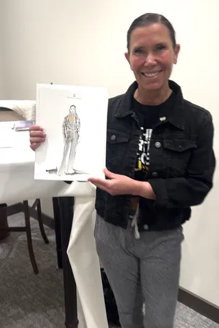 Smiling woman holding a fashion illustration indoors