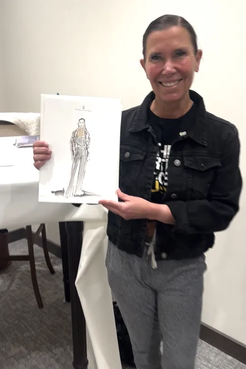 Smiling woman holding a fashion illustration indoors