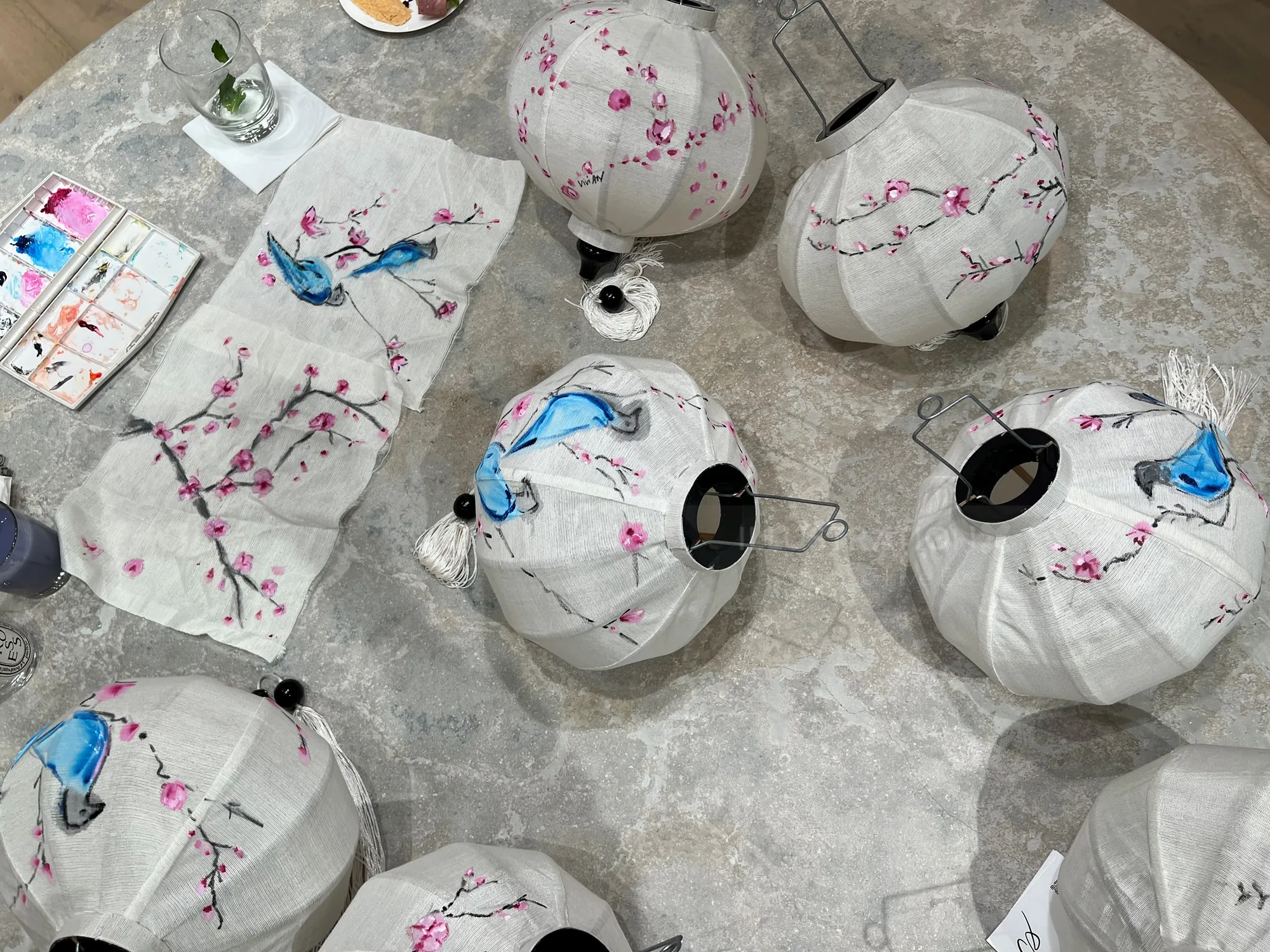 White paper lanterns painted with blue birds and pink cherry blossoms