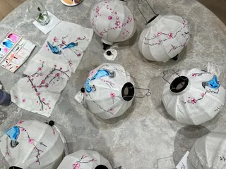 White paper lanterns painted with blue birds and pink cherry blossoms