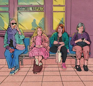 Four women sitting on bench in train station waiting area