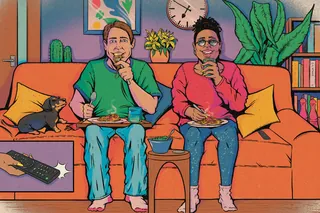 Couple sitting on sofa eating and drinking with a cat and plants around