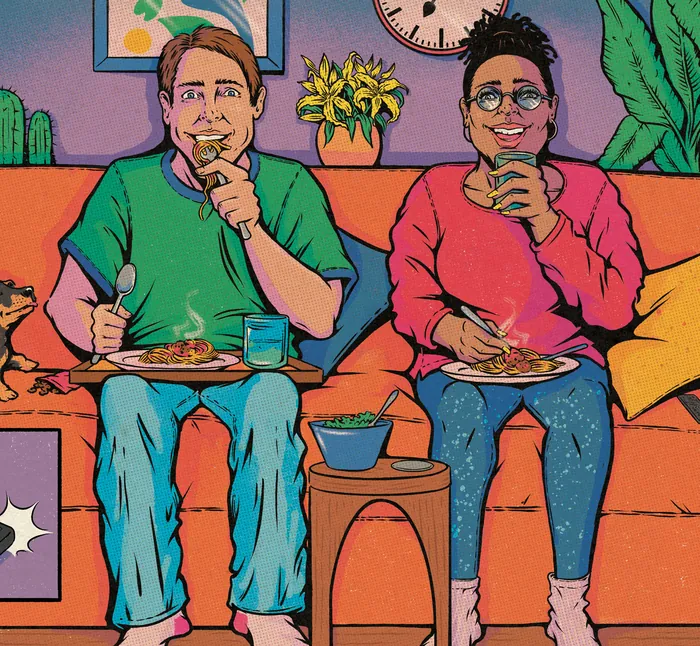 Two people sitting on a couch eating food and drinking beverages