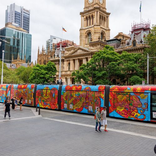 Brightly painted tram near historic city hall with people walking