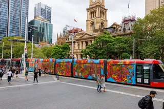 Brightly painted tram near historic city hall with people walking