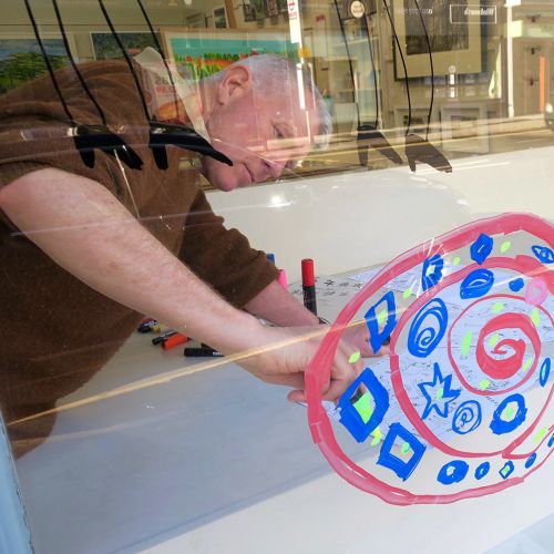 Man painting a vibrant snail design on a glass window