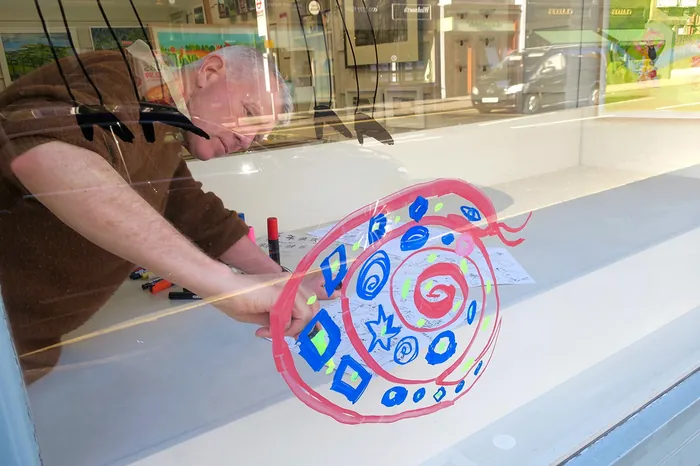 Man painting a vibrant snail design on a glass window