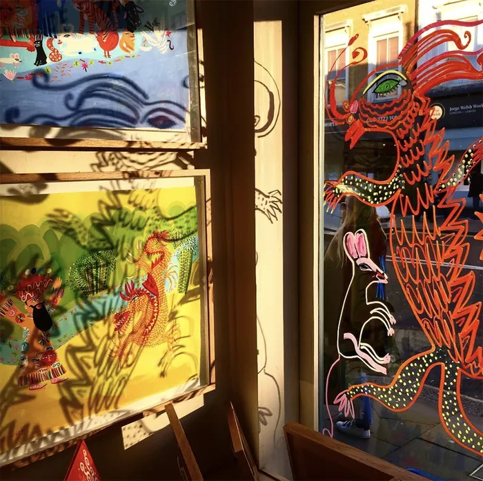 Bright dragon and mouse drawings on window glass with sunlight