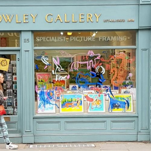 The Rowley Gallery shopfront with vibrant framed pictures and neon art in window.