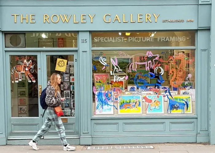 The Rowley Gallery shopfront with vibrant framed pictures and neon art in window.