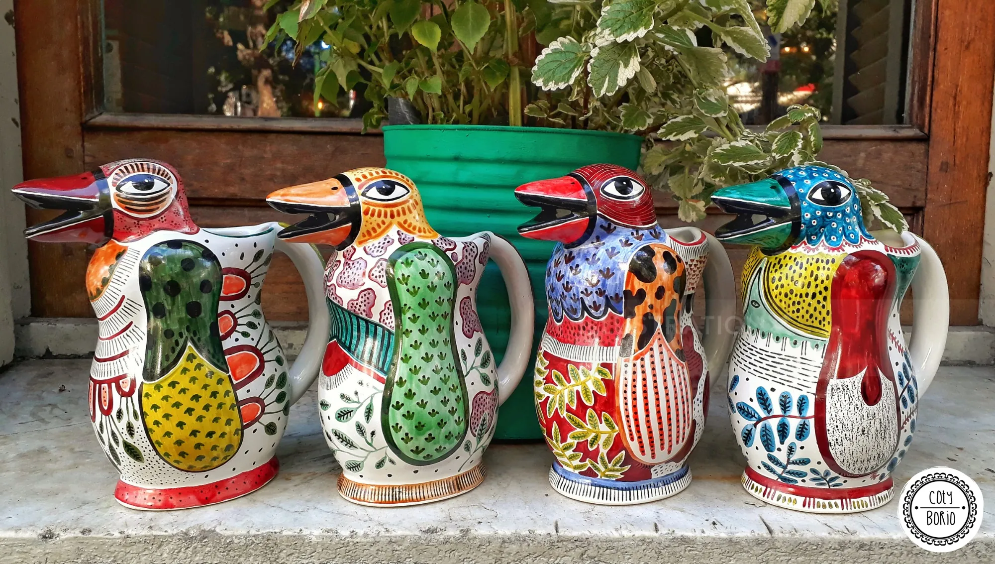 Les quatre pichets en céramique peints à la main et colorés de Coty Borio, représentant des pingouins