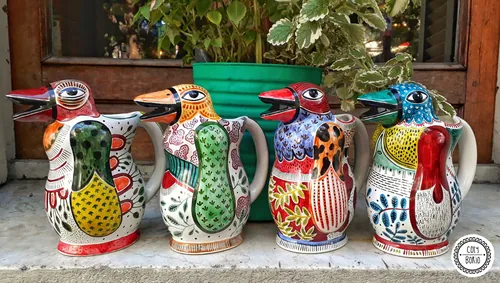 Les quatre pichets en céramique peints à la main et colorés de Coty Borio, représentant des pingouins
