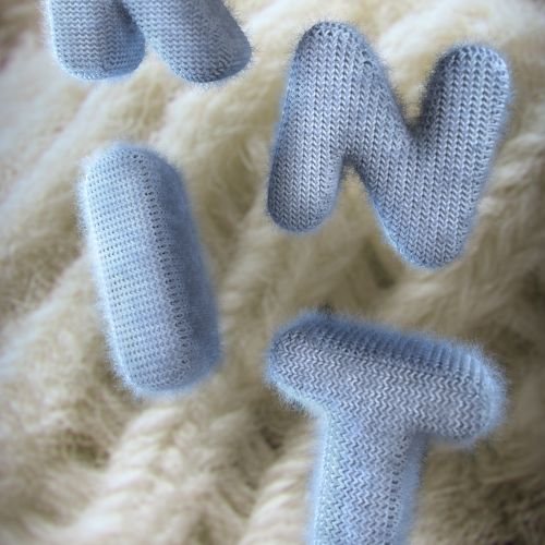 Soft fabric letters K, N, I, T on a knitted background