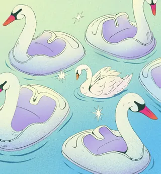 A swan swims among several swan-shaped pool floats on water