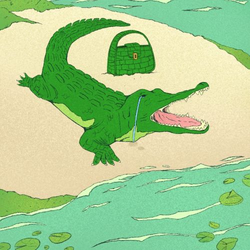 Green crocodile with an open mouth and handbag on sand