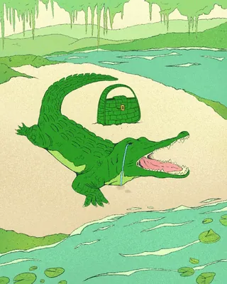 Green crocodile with an open mouth and handbag on sand