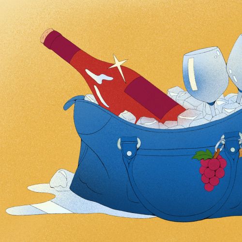 Bottle of wine chilling in ice bucket with wine glasses and grapes