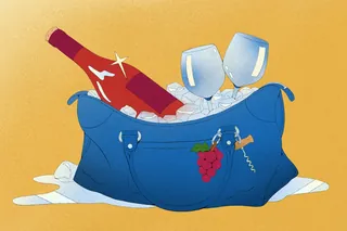 Bottle of wine chilling in ice bucket with wine glasses and grapes