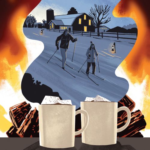Mother and daughter skiing at night with fire and hot drinks by Drew Bardana