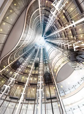Interior view looking up a high-rise elevator shaft with lights by Eberhard Reimann