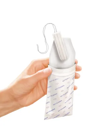 Hand holding a tampon with applicator and wrapper by Eberhard Reimann