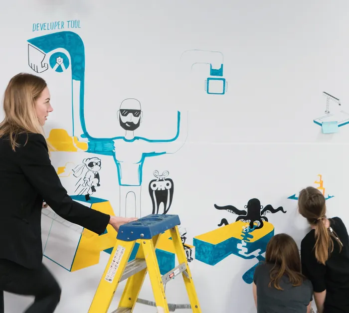 Adults and children painting creative wall mural with blue and black characters