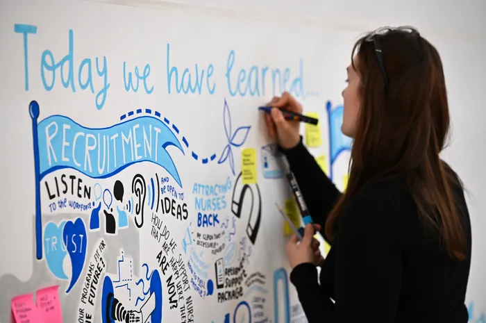 Woman writing recruitment ideas on whiteboard with colorful markers.