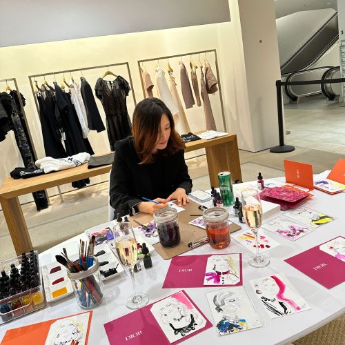 Artist Elise Lee drawing fashion sketches at Dior live event