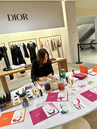 Artist Elise Lee drawing fashion sketches at Dior live event