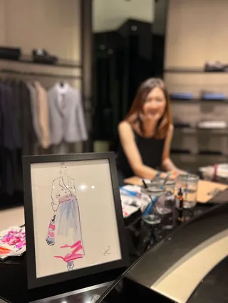 Fashion sketch with seated artist drawing at Emporio Armani event by Elise Lee