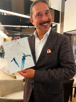 Smiling man in blazer holding abstract artwork by Elise Lee